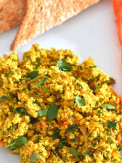 Indian-Style Tofu Scramble served on a white plate with 2 bread slices.