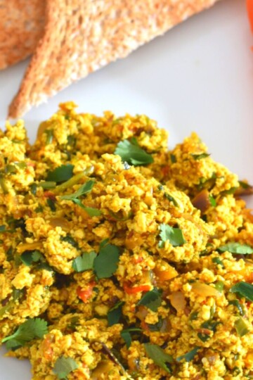Indian-Style Tofu Scramble served on a white plate with 2 bread slices.