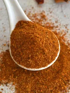 Close-up look of chole masala powder in a white spoon.