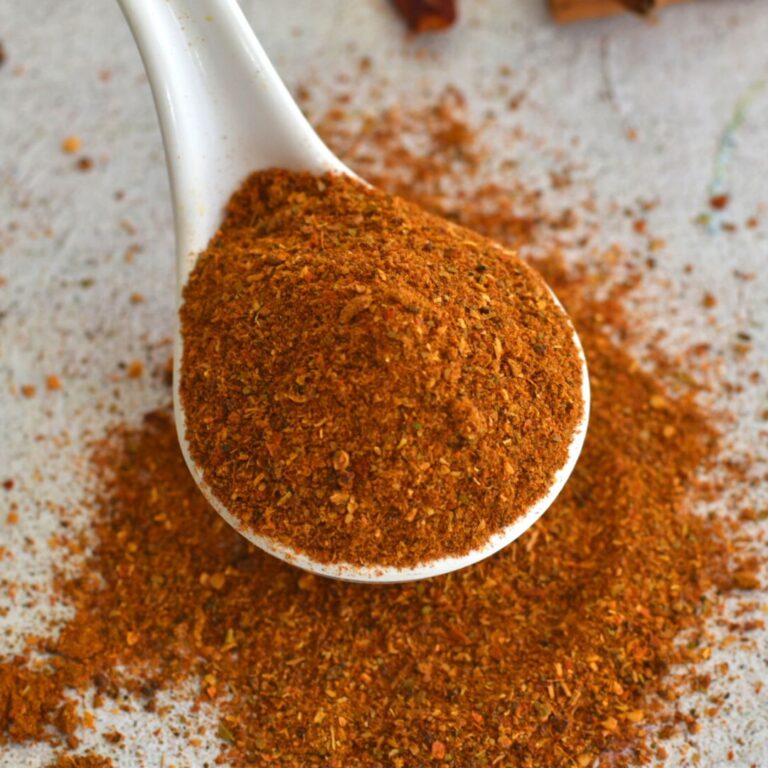 Close-up look of chole masala powder in a white spoon.