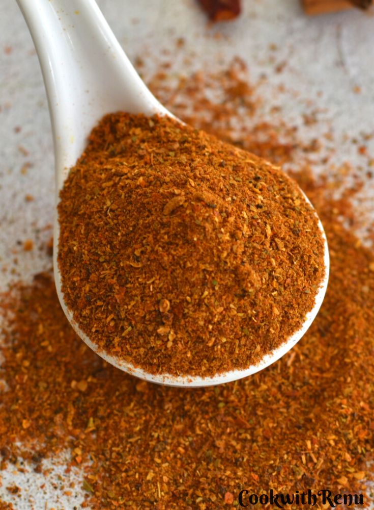 Close-up look of chole masala powder in a white spoon.