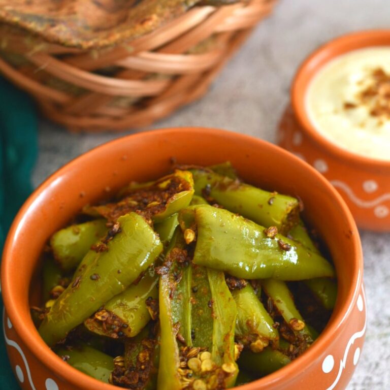 Close-up look of Hari Mirchi ke Tipore served in a brown designer bowl with yogurt and paratha.