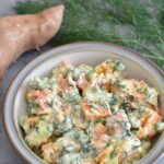 Vegan Sweet Potato and Fennel Fronds Salad served in grey bowl with gold linking. 1 sweet potato and few fennel fronds seed in background.