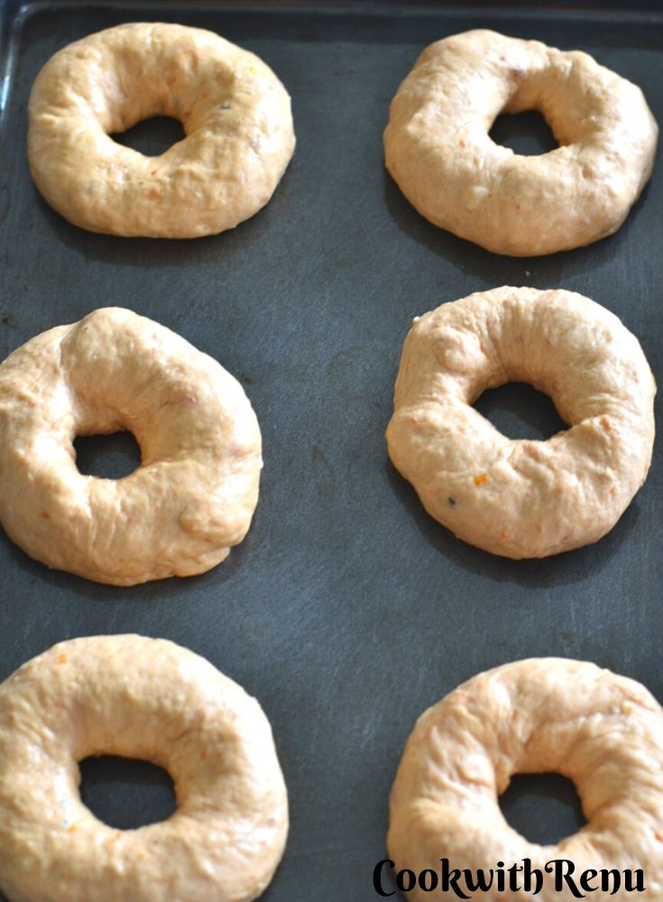 Bagels getting proofed in an oven tray.