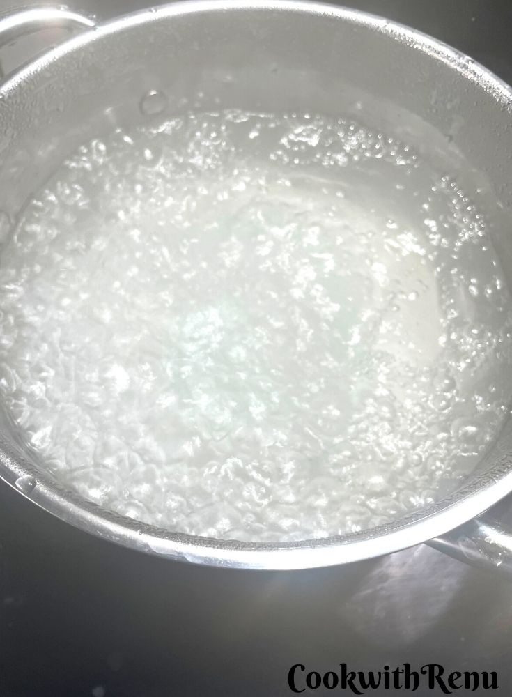 Bagels ready to be boiled in water in a pot.