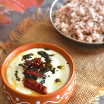 Pavakka Pachadi served in a brown designer bowl. Served in the background is some red matta rice.