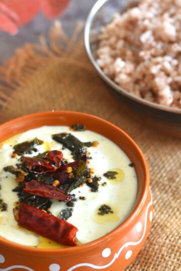 Pavakka Pachadi served in a brown designer bowl. Served in the background is some red matta rice.