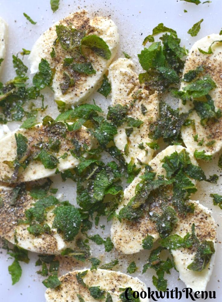 Mozzarella Cheese marinated with mint and black pepper on a white board.