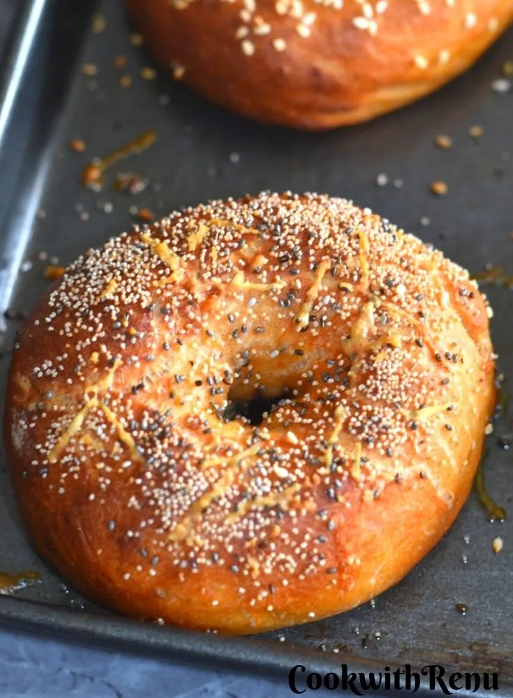 Baked Savoury Bagels topped with cheese and sesame seeds on a baking tray.