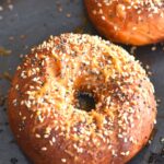 Baked Savoury Bagels topped with cheese and sesame seeds on a baking tray.