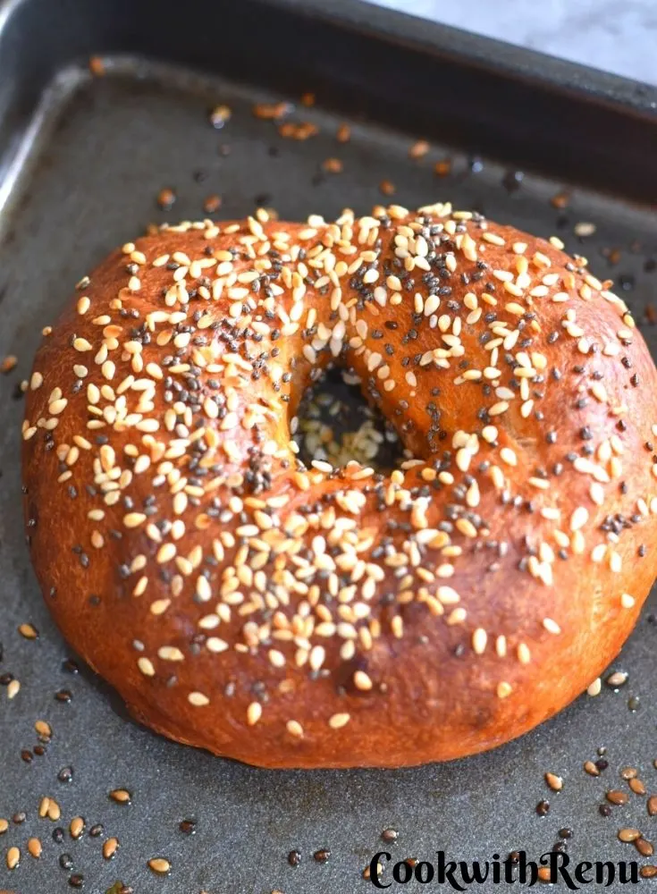 Baked Savoury Bagels topped with sesame seeds on a baking tray.