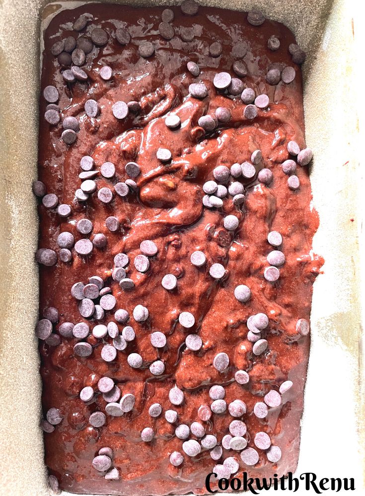 Chocolate banana bread ready to be baked in a loaf tin, with chocolate chips on top.