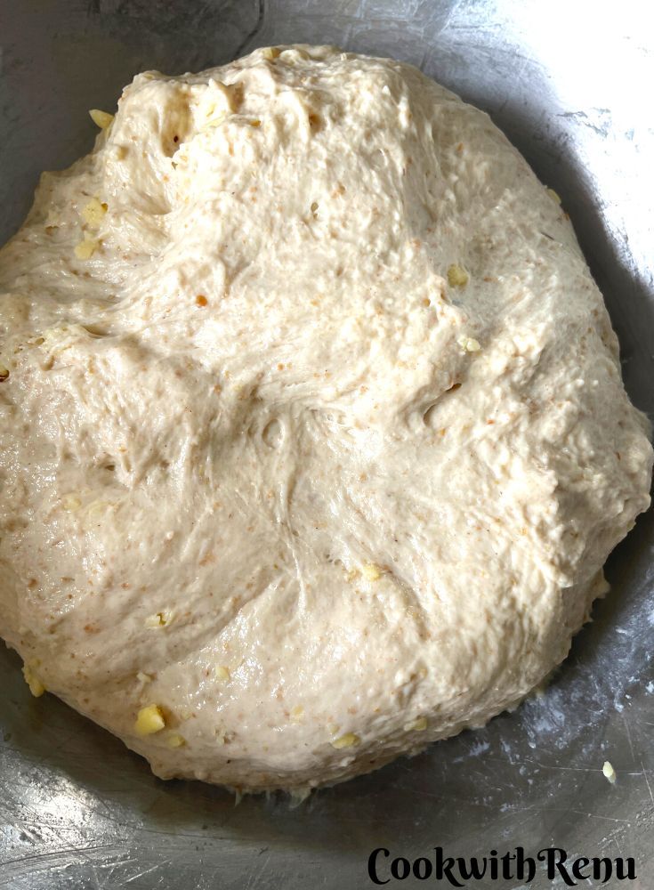 Grated cheese and apple added in dough in a bowl.