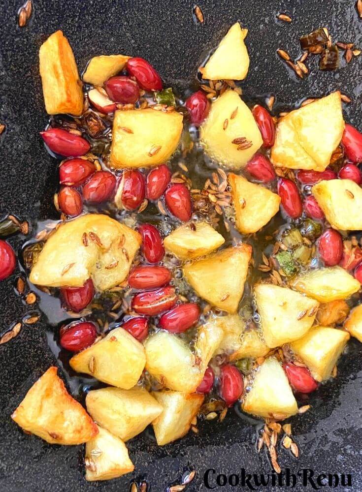 Peanut, potato and green chili cooked in ghee in a cast iron wok.