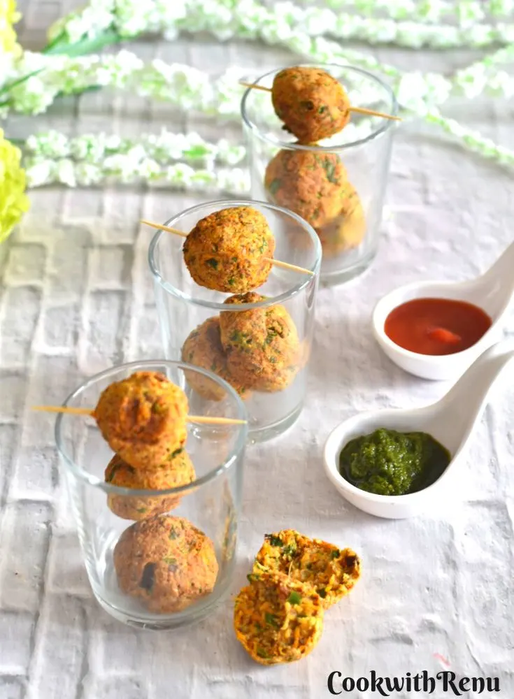 Air Fryer Vegetable Paneer Kofta served in small glasses. Seen in the front is a cut kofta showing the inside texture and served along with green coriander chutney and tomato ketchup.