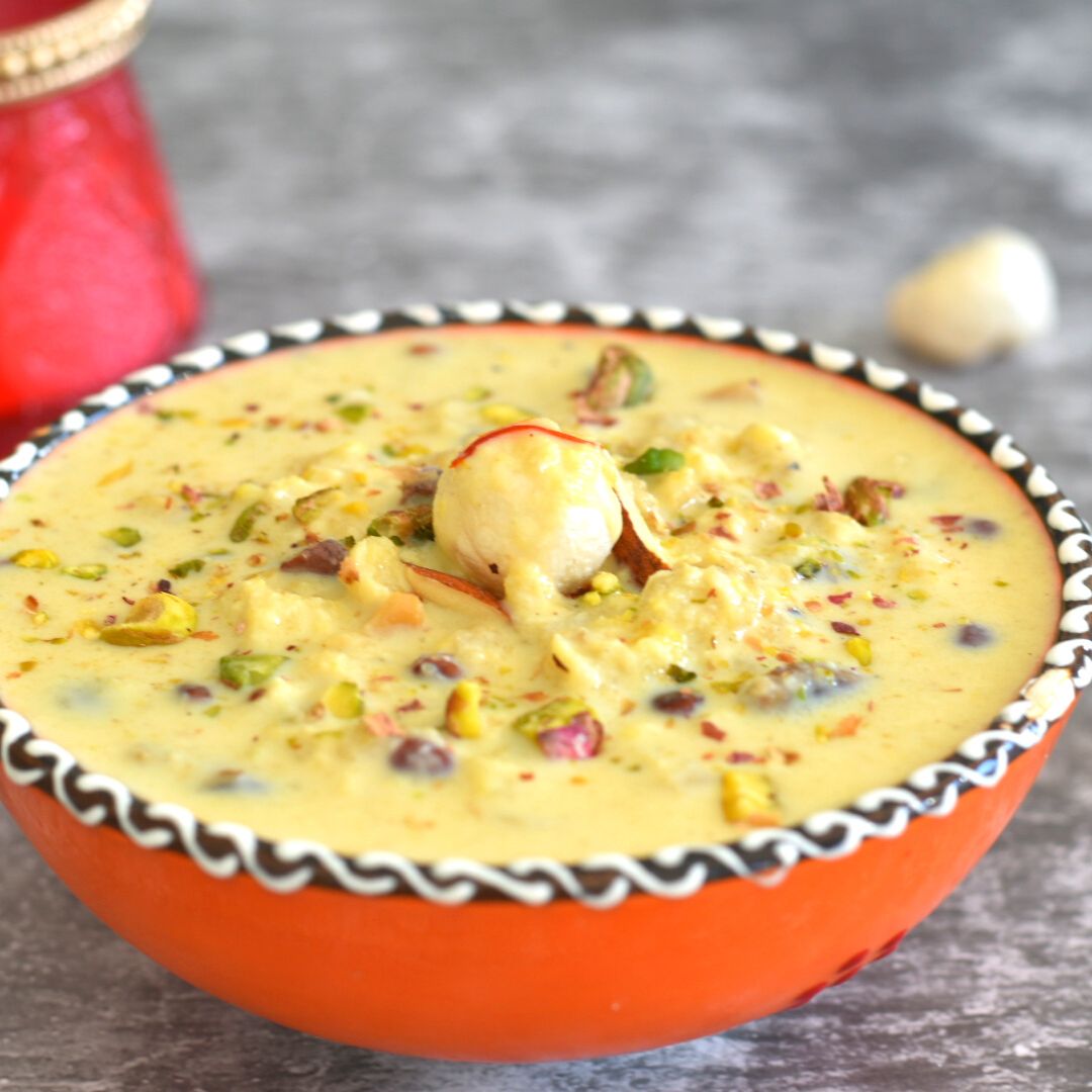 Phool Makhana Kheer served in an orange designer bowl. Seen in the background is some makhana and a candle.