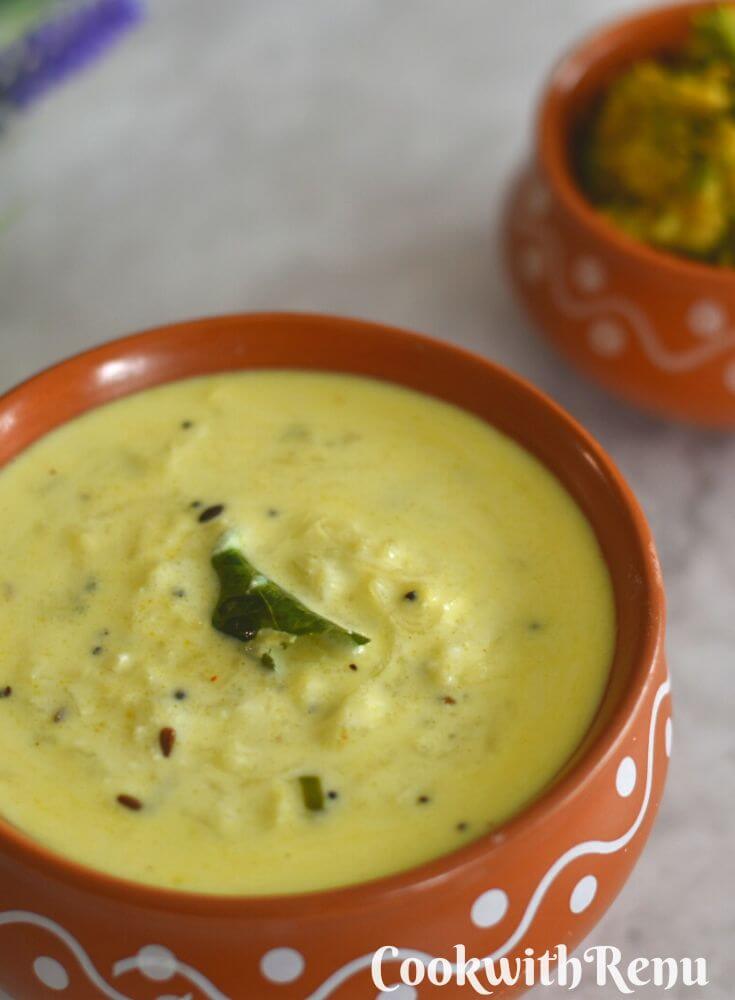 Dudhi Raita served in a brown designer bowl, with some arbi bhaji seen in the background.