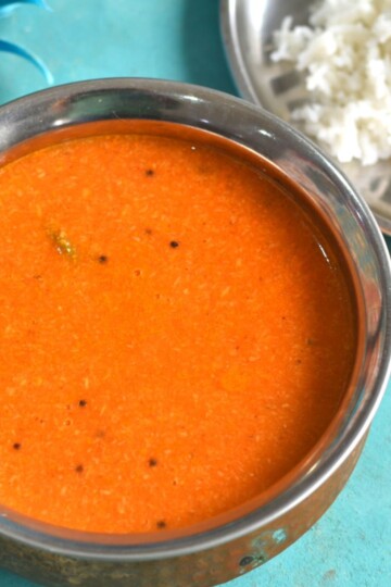 Close up look of Maharashtrian Tomato Saar served in a copper vessel along with some rice on the side.