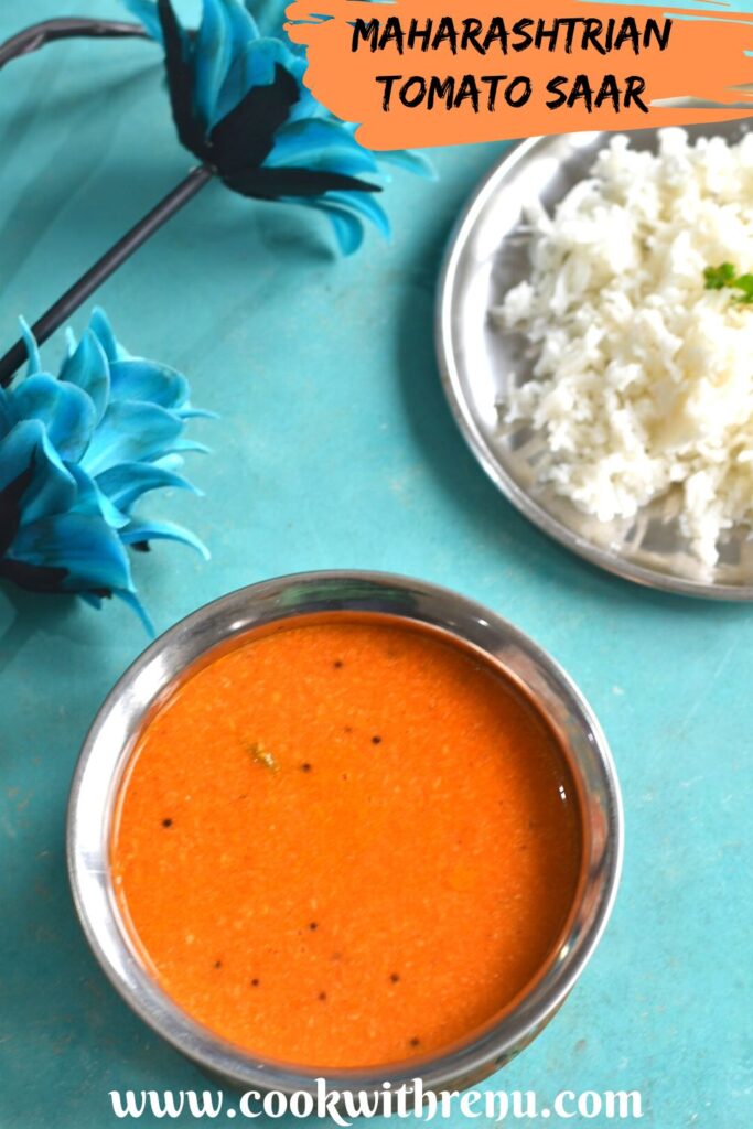 Close up look of Maharashtrian Tomato Saar served in a copper vessel along with some rice on the side. Seen are some artificial flowers too on the side.