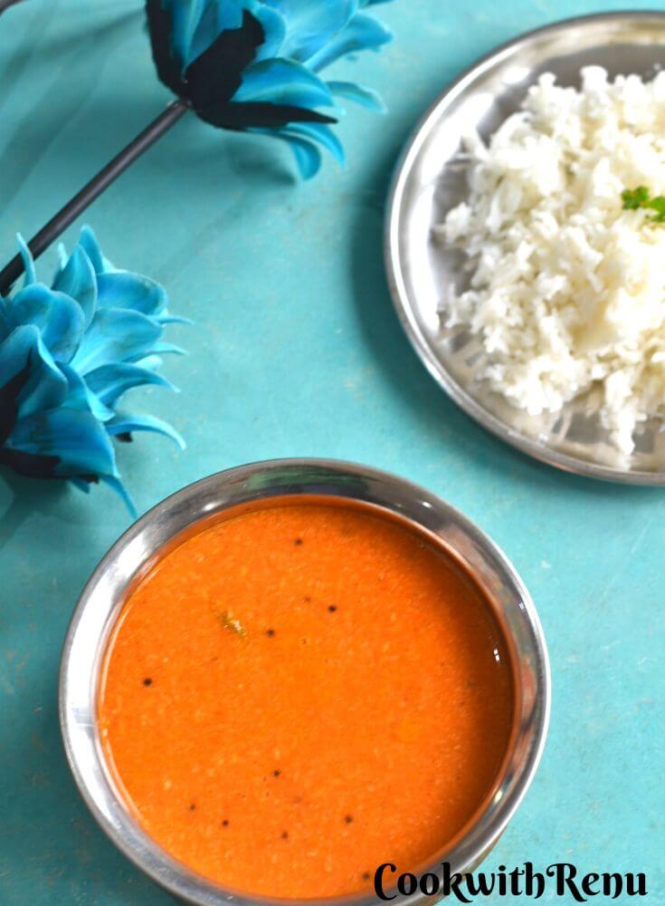 Close up look of Maharashtrian Tomato Saar served in a copper vessel along with some rice on the side.