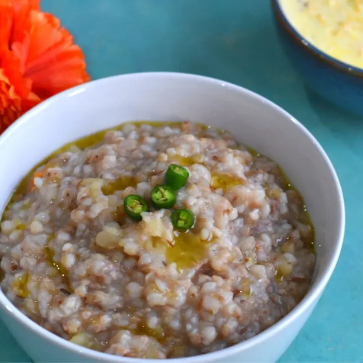 Farali Kuttu ki khichdi served in a white bowl with a drizzle of ghee and a topping of green chili.