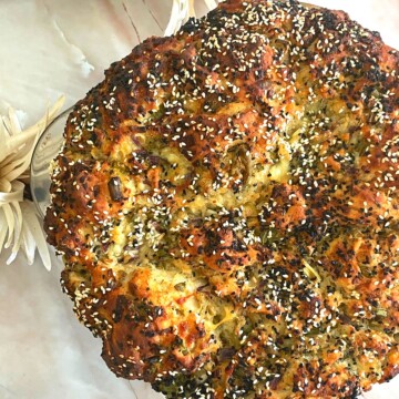 Top view of Halloumi Cheese, Olive, and Mint half bread. Seen in the background are some flowers.