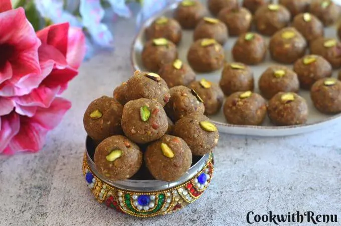Methi and Gond Ladoo in a designer multi colour box with a few ladoos seen behind in a plate.