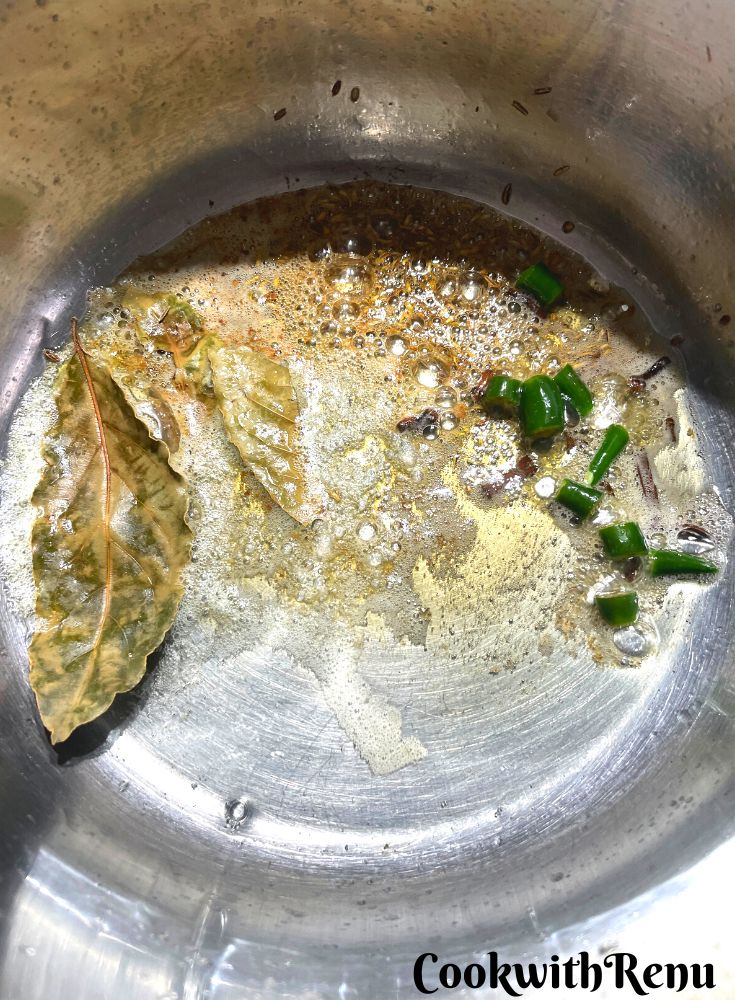 Adding of spices and green chili in a pan.