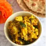 Arbi Masala or dry veg in a white bowl, with buckwheat roti seen behind.