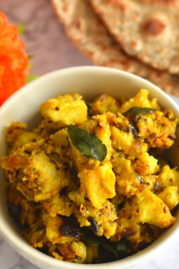 Arbi Masala or dry veg in a white bowl, with buckwheat roti seen behind.