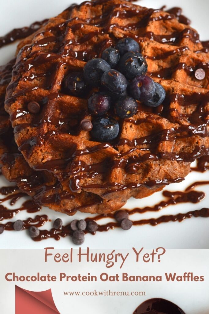 Chocolate Protein Oat Banana Waffles with a drizzle of chocolate and a garnish of chocolate chips and blueberries.