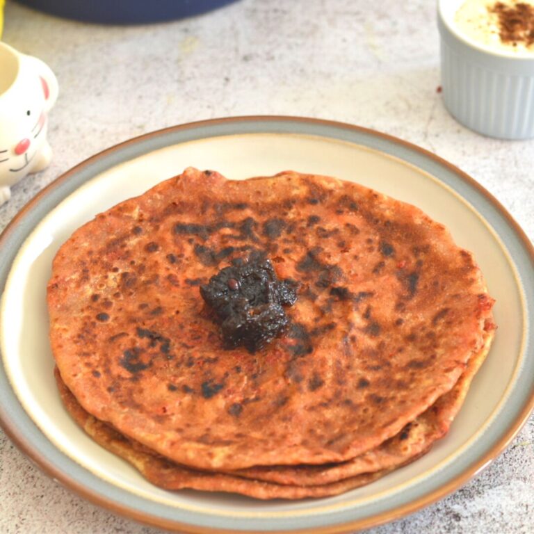 Leftover Veg and Paneer Paratha served in a plate with grey and brown lining. Lemon oil free pickle is served on top.