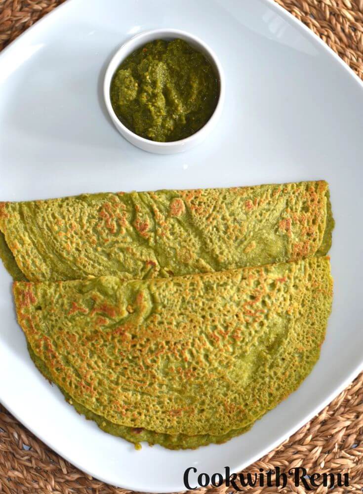 Top view of Oats and Lentil Pancakes served with coriander chutney in a white rectangular plate