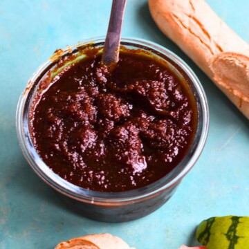 Instant Pot Watermelon Rind Jam in a glass container with some gluten-free baguette and watermelon rind in the background.