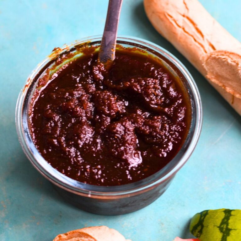 Instant Pot Watermelon Rind Jam in a glass container with some gluten-free baguette and watermelon rind in the background.
