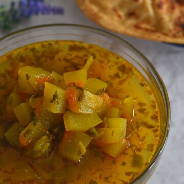 Watermelon Rind Sabji served in a glass bowl with some paratha on the side.
