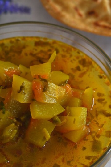 Watermelon Rind Sabji served in a glass bowl with some paratha on the side.