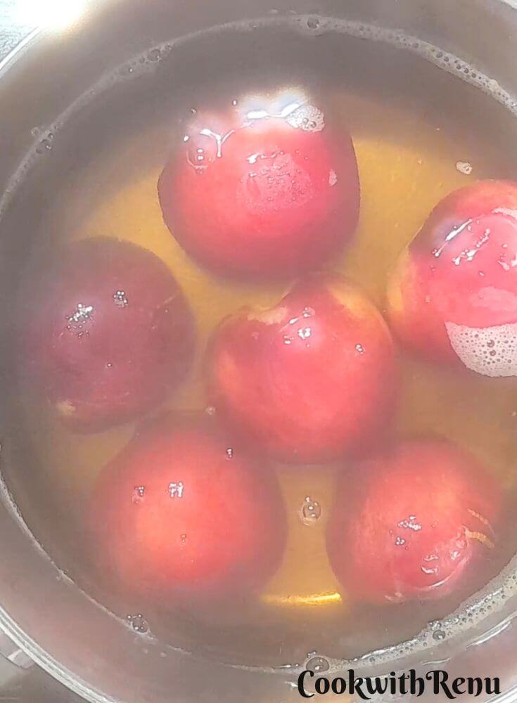 Peaches poached in Sugar and Vanilla Syrup in a pot.