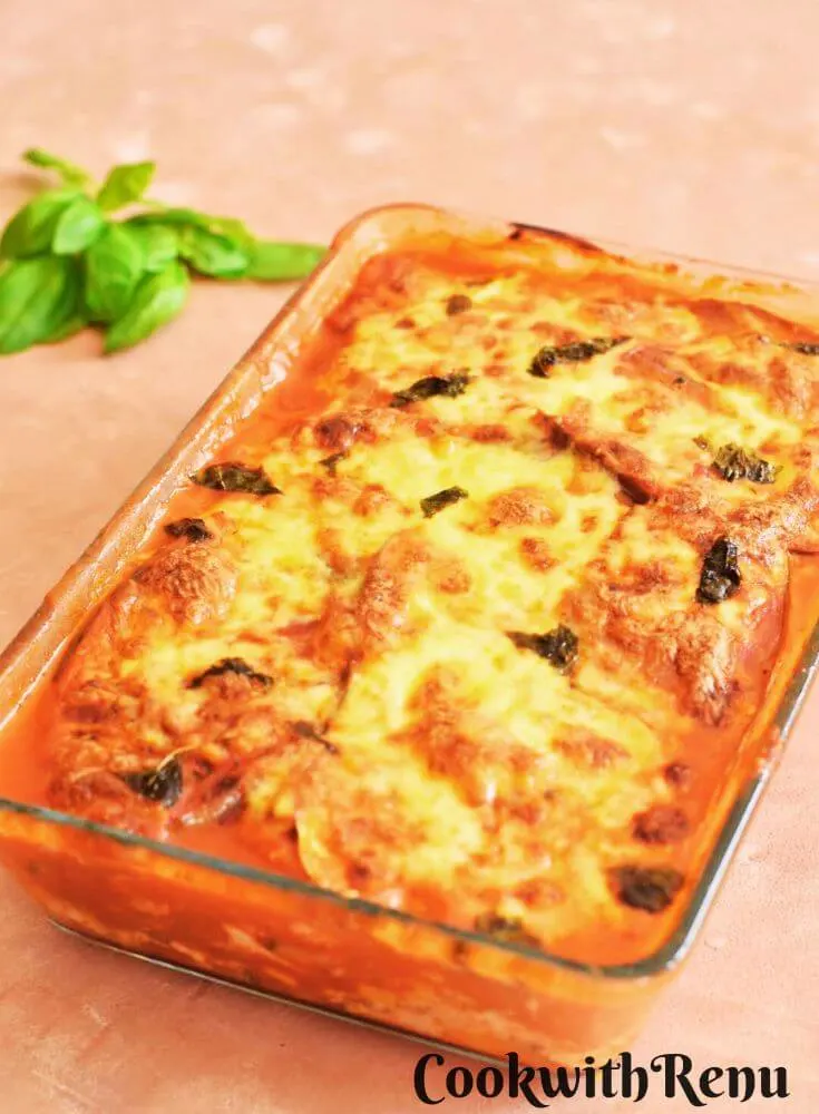 Zucchini and Aubergine Lasagna in a baking tray with few basil leaves on the side.