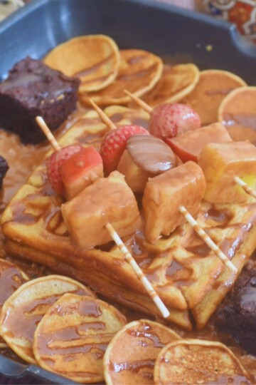 Waffles, pancakes, brownies, and a fruit sizzler on a grill pan.