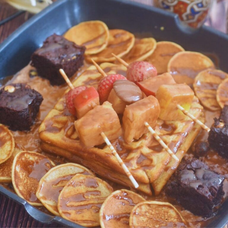 Waffles, pancakes, brownies, and a fruit sizzler on a grill pan.