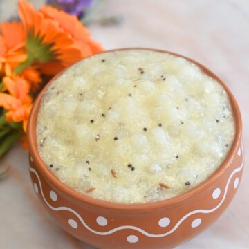 Farali Sabudana Kadhi served in a brown designer bowl, with some fresh calendula flowers seen in the background.