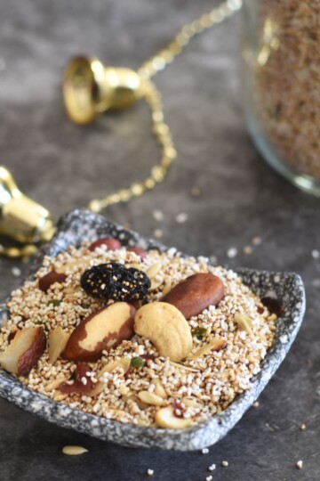 Amaranth Trail mix served in a small black plate. Seen in the background is some golden bells and a jar filled with rajgira.