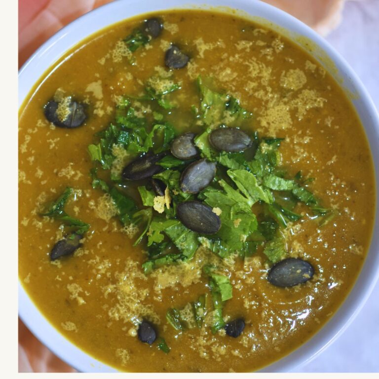 Top view of Soup served in a white bowl with a topping of seeds and celery leaves.