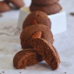 Few Whole Wheat Chocolate Nankhatai arrranged on a white sheet. In the front is one half of nankhatai showing the texture of inside.
