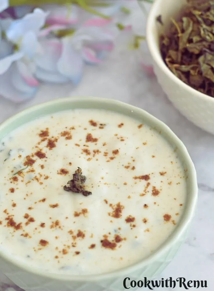 Bathua raita served in a bowl. Seen in the background are some dry bathua leaves.