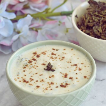Bathua raita served in a bowl. Seen in the background are some dry bathua leaves.