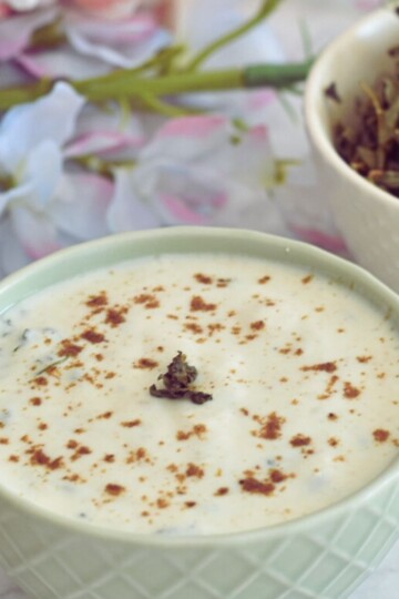 Bathua raita served in a bowl. Seen in the background are some dry bathua leaves.