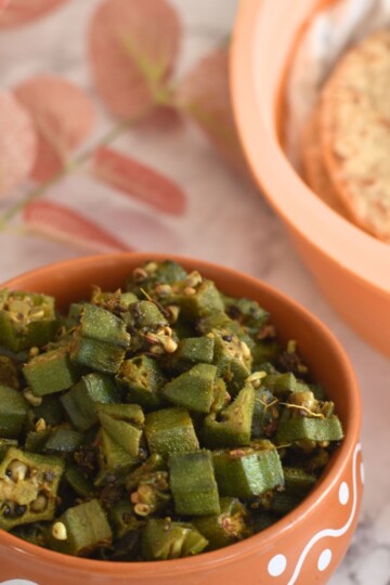 No Onion No Garlic Bhindi served in a brown deisgner bowl. Some roti in the background.