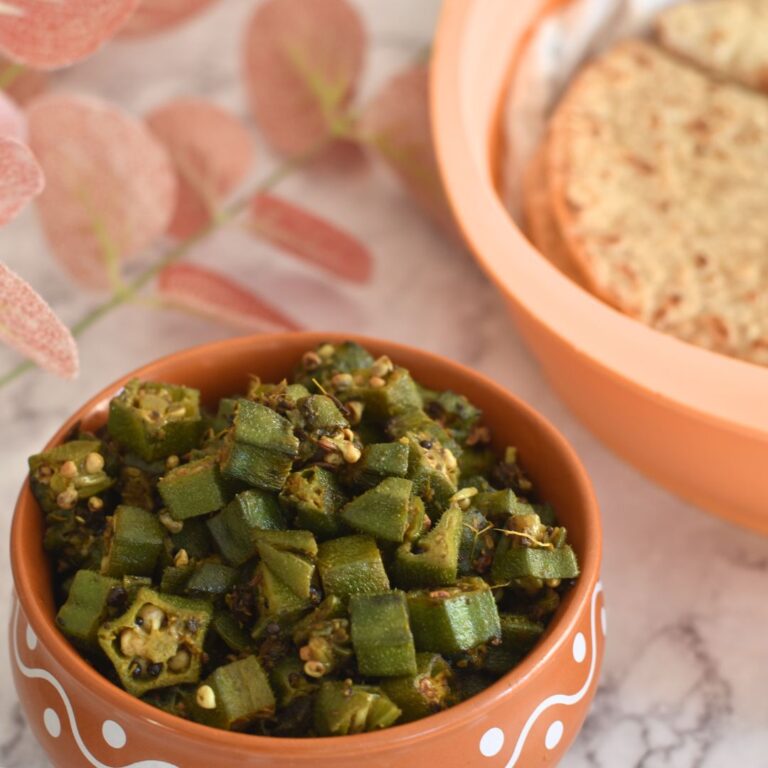 No Onion No Garlic Bhindi served in a brown deisgner bowl. Some roti in the background.